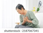 Small photo of Asian senior woman having a palpitation of the heart at home