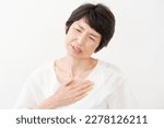 Small photo of Asian middle aged woman having a palpitation of the heart in white background