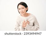 Small photo of Asian middle aged woman having a palpitation of the heart in white background