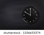 Small photo of Black wall clock showing ten o'clock on black chalkboard background. Office clock showing 10am or 10pm on black texture