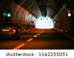 Small photo of Two lines highway tunnel with one car driving on the right line to the exit on the end.