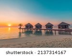 Maldives island sunset. Water bungalows resort at islands beach. Indian Ocean, Maldives. Beautiful sunset landscape, luxury resort villas and colorful sky. Summer vacation holiday and travel concept