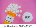 Small photo of Prednisone Rx medicine pills in plactic vial with tablets. Pills spilling from yellow container on pink background.