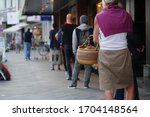 Low angle and selected focus, European people queue and wait for shopping on sidewalk outside supermarket during quarantine for COVID-19 virus in Düsseldorf, Germany.