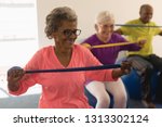 Front view of happy diverse senior woman exercising with resistance band in fitness studio