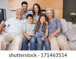 Small photo of Portrait of smiling extended family sitting on sofa in the living room at home