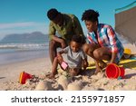 Small photo of African american young parents looking at son playing with sand at beach against sky on sunny day. summer, nature, unaltered, beach, childhood, family, togetherness, lifestyle, enjoyment, holiday.