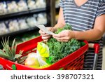 Woman with red basket holding list in supermarket