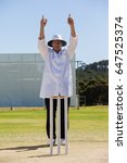 Cricket umpire signalling six...
