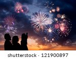 The happy family looks beautiful colorful holiday fireworks in the evening sky with majestic clouds,  long exposure