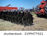 Large modern plow or disc harrow for cultivating the land. Tractor plows a piece of land in a field.