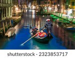 Venetian gondolier punting gondola through green canal waters at night - Venice Italy
