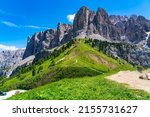 View of Sella Group in the Italian Dolomites with green grass hill and yellow flowers at Gardena Pass in sunny day at South Tyrol, Italy.