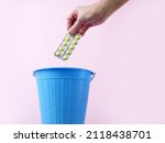 Hand throwing pills away, trash bin with pills and blisters inside, medecine in trashcan, pharmaceutical waste, expired medicines concept, closeup