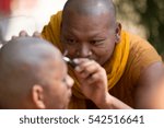 Small photo of Pattani, Thailand - April 6, 2015: Monk of Maprangman Temple use razor get eye brown off face for preparation a man to be Monk in Buddhism Religion.
