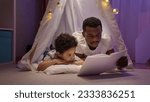 Small photo of African American father reads fairytale to delighted preschooler son in wigwam.