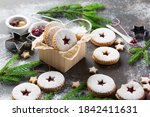 Linzer Christmas or New Year cookies filled with jam and dusted with sugar on dark background. Traditional Austrian Christmas cookies. Homemade sweet present in festive box.