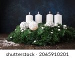 Festive stylish winter Christmas wreath. Modern Christmas wreath with white candles, green branches and snowflakes on green background. Holiday Advent time, copy space.