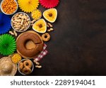 Small photo of Festa Junina Summer Festival Carnival concept. Brazilian straw hat, Corn Cake, peanuts and colorful flags on wooden background, top view. Design for Greeting Card, Invitation or Holiday Poster