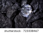 A single solitaire Diamond in amongst some pieces of coal. 