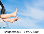 feet of a young girl from the window of a car on a background of blue sky
