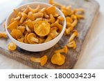 Raw chanterelle mushrooms on a white bowl on wooden background. Food background with yellow mushrooms