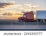 Industrial long hauler big rig burgundy semi truck tractor with chrome parts transporting commercial cargo in loaded dry van semi trailer running on the highway road at sunset time in California