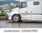 Small photo of Broken after an accidental collision big rig semi truck tractor with body damage standing out of service on the highway road shoulder waiting for road assistant mobile towing truck for help