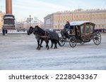 Small photo of St. Petersburg, Russia - January 08, 2022: A carriage drawn by two black horses on Palace Square. Horse-drawn carriage ride on Palace Square is a romantic attraction for tourists