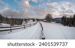 Small photo of Secondary countryside alpine road in remote mountain village, snow drifts and wood fence on wayside
