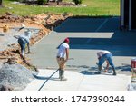 Unidentifiable hispanic men working on a new concrete driveway at a residential home