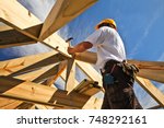Roofer, carpenter working on roof structure on construction site