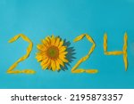 Sunflower petals in the form of numbers 2024 on a blue background. 2024 new year new reality. Summer it is time for traveling