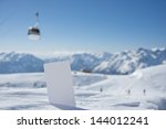 Small photo of Lift pass card in snow with blurred ski-lift cable car and mountain range. Concept to illustrate winter sport admission fee