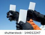 Small photo of Gloved hands holding lift pass against blue sky. Concept to illustrate ski admission fee