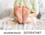 Woman relaxing in bedroom, female feet with dry cracked skin close-up, foot care concept, home interior