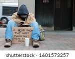 Depressed Panhandler Sitting With A Cup And Sign