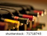 Red wine bottles stacked on wooden racks shot with limited depth of field