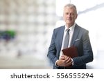 Shot of an elderly managing director with diary standing in conference room after business meeting. 