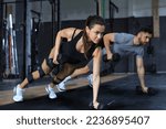 Small photo of Strong man and woman holding dumbbells in plank position at the gym