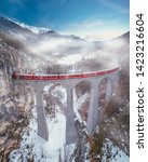 Small photo of Filisur, Switzerland - March 05, 2018: Red train over the Landwasser Viaduct in winter with fog