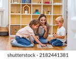 Small photo of Mother playing with children a Tic-Tac-Toe game. Educational games for kids. Mother-children creative time together.