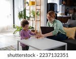 Small photo of Mother looking at a child playing with an educational didactic toy. Young woman and child playing with didactic toys