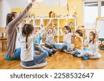 Small photo of Kindergarten teacher with children sitting on the floor having music class, using various instruments and percussion. Early music education