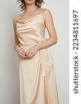 Small photo of Female model wearing golden camisole silk top and wrapped midi skirt. Stylish monochrome summer outfit. Fashion Studio shot.