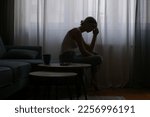 Young depressed woman sitting on the sofa next to the window	