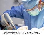 Small photo of Close up photo of orthopaedic surgeon inside operating room. Doctor in blue surgical gown suit intense perform orthopaedic surgery with team of assistants.Medical concept.