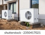 Small photo of Two air source heat pumps installed outside of new and modern city house under construction, green renewable energy concept of heat pump