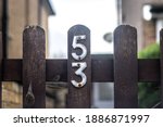 Small photo of Somber and dark is number 53 on a wooden gate