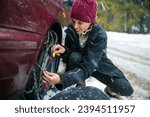 Determined Mid Adult Woman Close-Up, Facing Cold Weather Challenges while Installing Tire Chains for Covered in Snow Slippery Roads